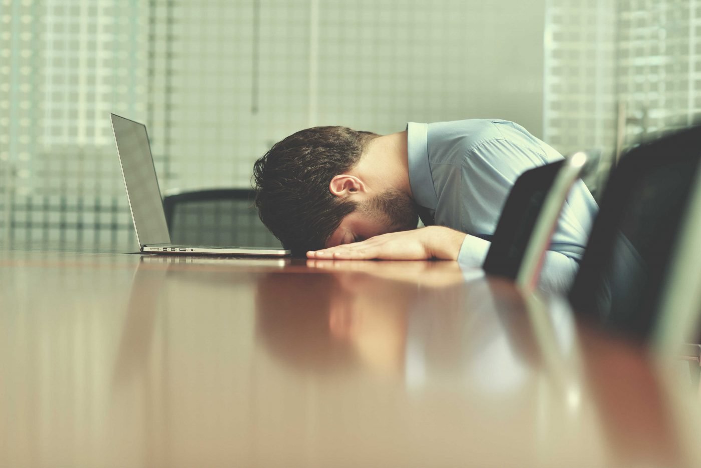homem com a cabeça baixa na mesa com o notebook na frente - liderança estratégica
